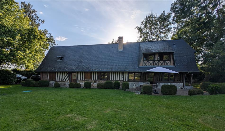 A large house presumably a converted barn in the French style surrounded by grass and trees