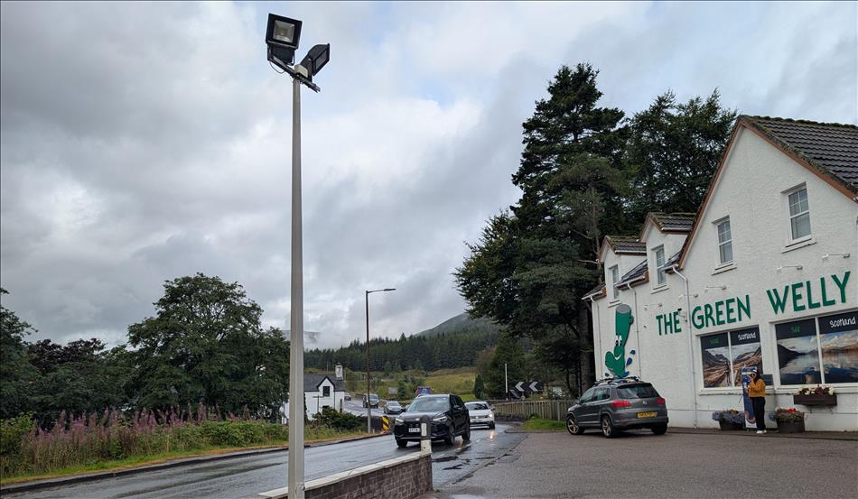 The side of a building with the Green Welly logo and the road leading off to Glencoe