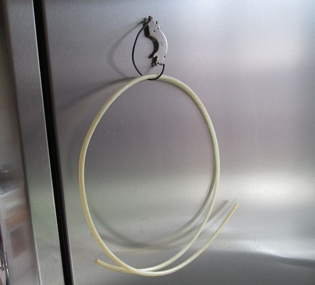 a plastic pipe hanging from a fridge magnet
