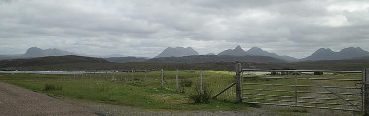 A road in the foreground with a long line of mountain tops behind at Achiltibuei