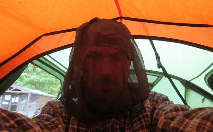 Ren is inside his tent with his dark black midge net over his head