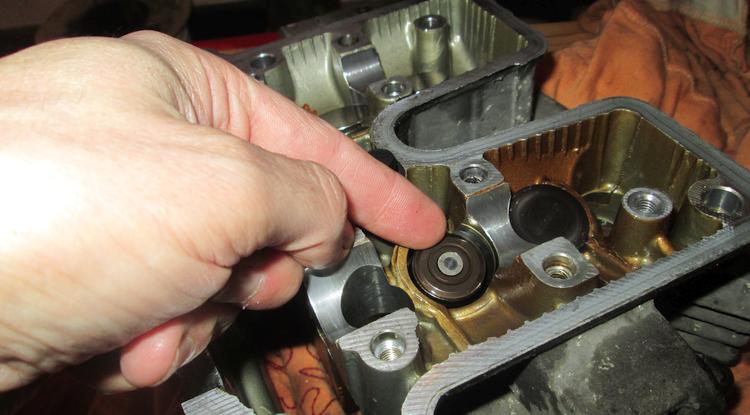Ren's finger points to a shim at the top of the valve stem