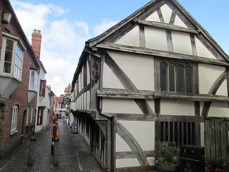 A narrow lane with timber framed and old brick buildings in Ledbury