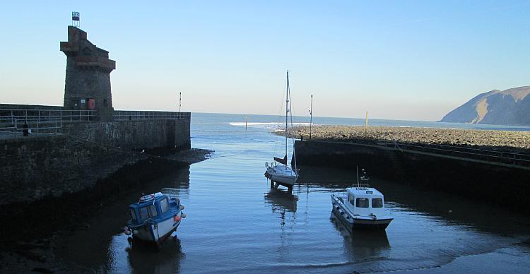 A few small boats lie in the mud of Lynmouth harbour while the tide is out