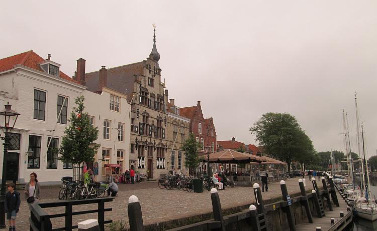 Dutch style buildings line a block paved road then the harbour at Veere