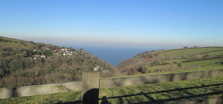A steep valley falls down to a tiny hamlet nestled by the coast of Devon