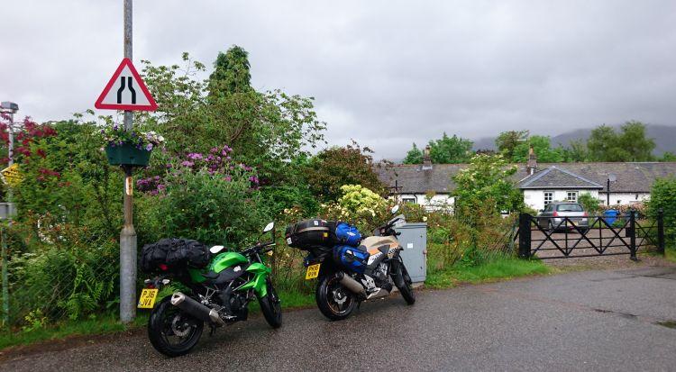 Ren and Sharon's bikes are parked outside a white pained house with a garden overflowing with flowers