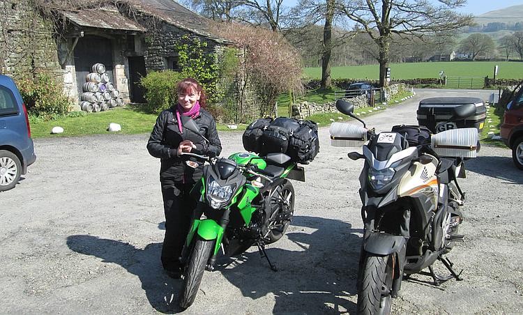 Sharon smiling in the sun next to her and Ren's motorcycles