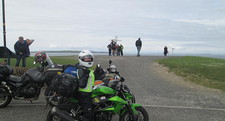 Sharon gives the thumbs up on her bike with the John O'Groats sign behind her